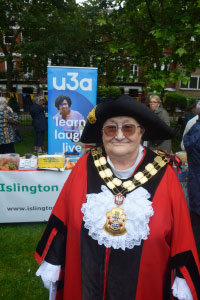 A woman reading a red cape standing in front of a poster