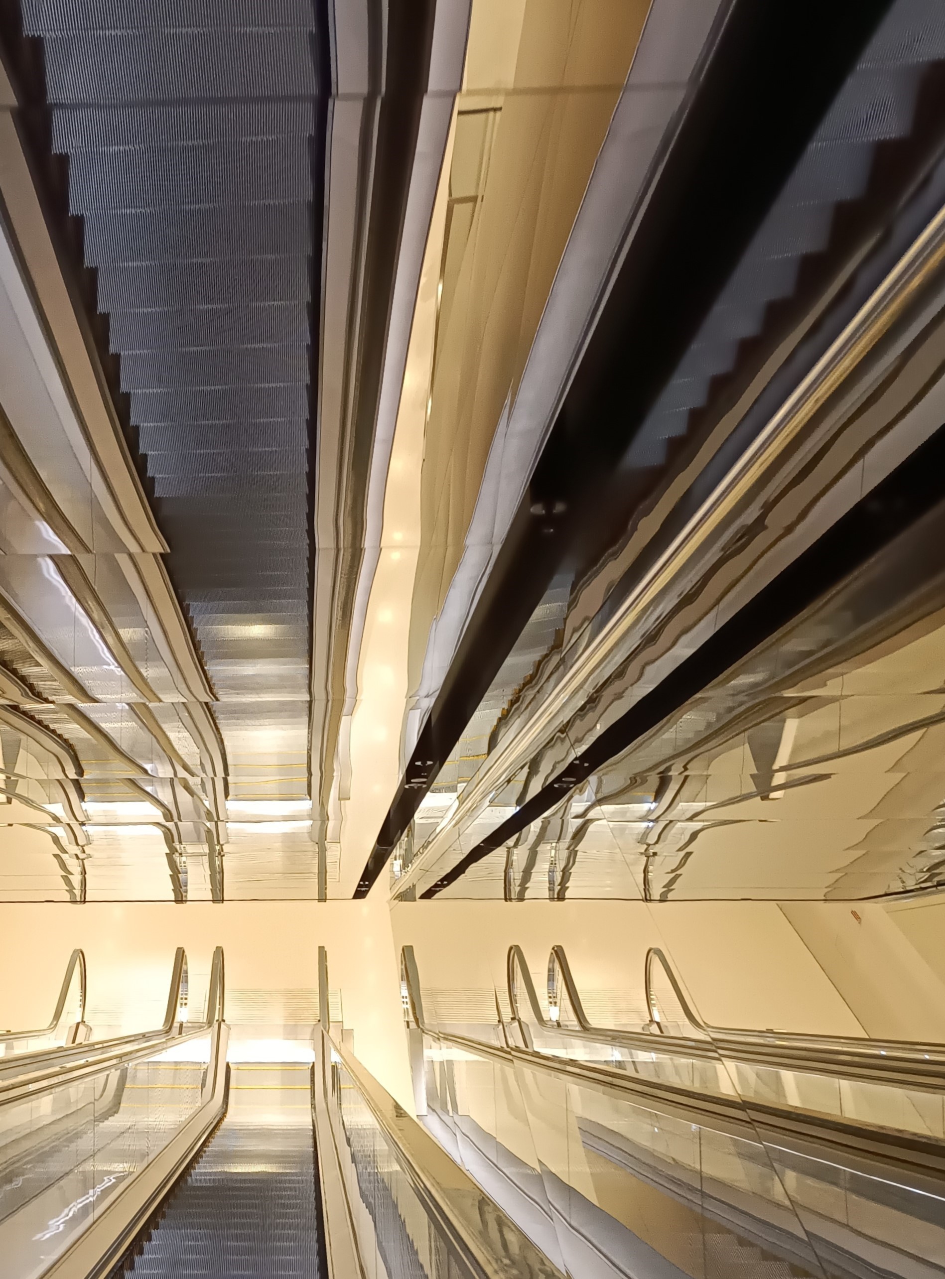 the view down an escalator whcih is also reflected onto the ceiling
