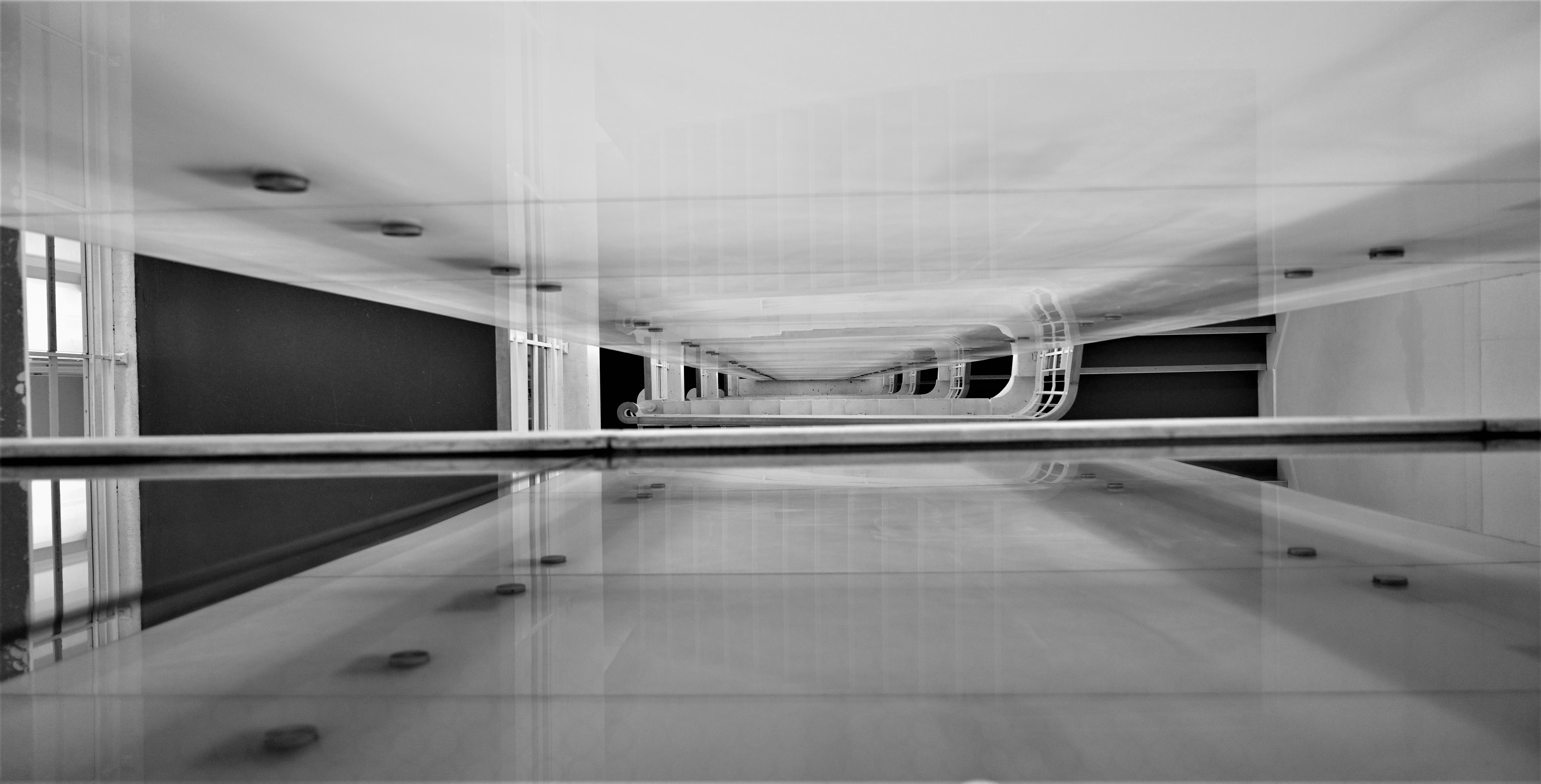 black and white photo view down sets of stairs, looks reflected