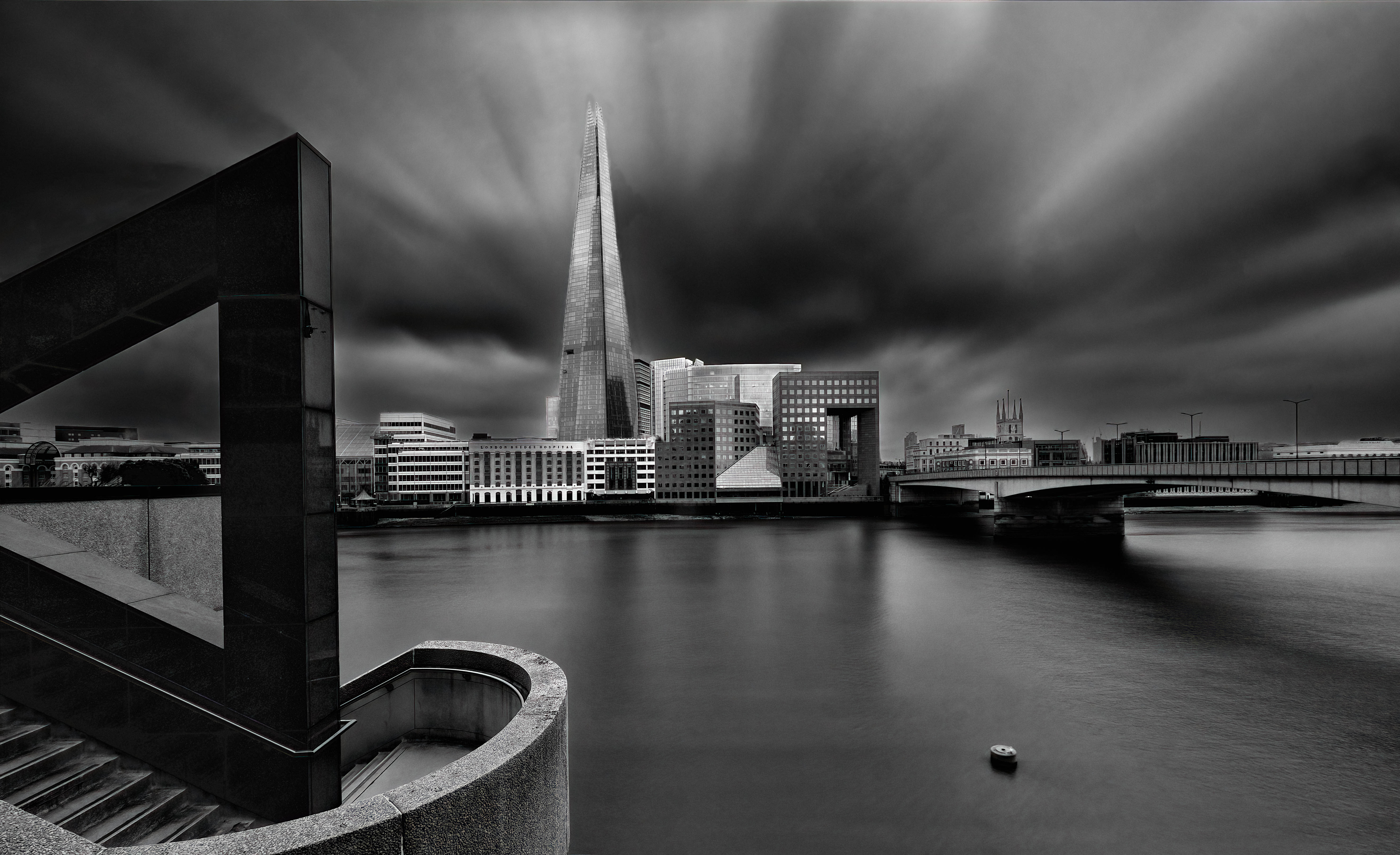 black and white photo of the thames river with the shard pointy building in the background