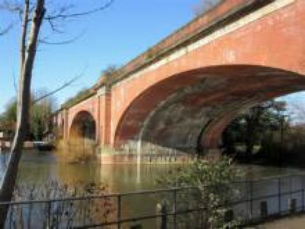 a river flowing under the red arch of a bridge